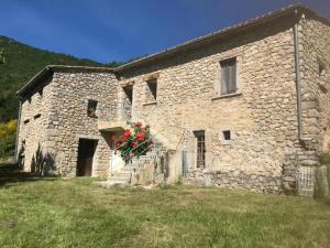 un edificio de piedra con un ramo de flores rojas en una cesta en Ferme de Fonfroide Location à la semaine en La Motte-Chalançon