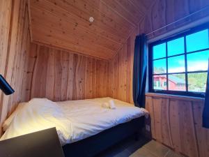 małe łóżko w drewnianym pokoju z oknem w obiekcie Fanøy Island Lodge 