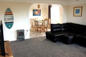 a living room with a black leather couch and a table at Parc Trethias in St Merryn