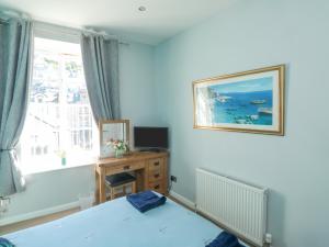 een slaapkamer met een bed, een bureau en een raam bij 4 Old Mill Court in Brixham