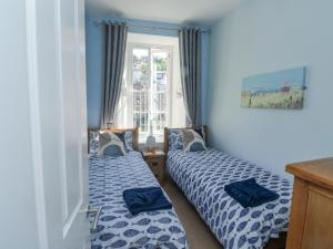 twee bedden in een kamer met blauwe muren en een raam bij 4 Old Mill Court in Brixham