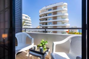 a balcony with two chairs and a table and a building at Peale's 2-Bedroom Apartment in Mackenzie in Larnaca