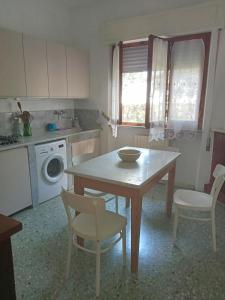 een keuken met een tafel en stoelen en een wasmachine bij Casa del Nonno in Pietrasanta