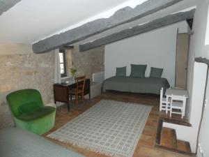 een slaapkamer met een bed, een bureau en een groene stoel bij Le Jas des aiguiers in Saint-Saturnin-dʼApt