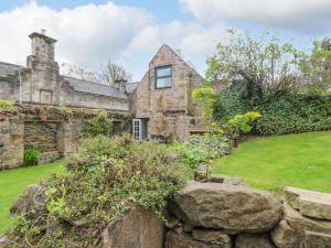 an old stone house with a stone wall at Dunira in Cupar