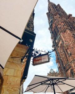 un letrero de la calle frente a un edificio con una torre en Maison Kammerzell - Hotel & Restaurant en Estrasburgo