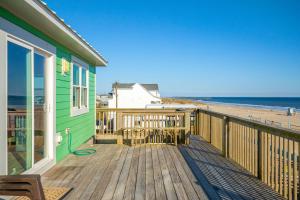 a deck with a green house and the beach at Suncatcher home in Atlantic Beach