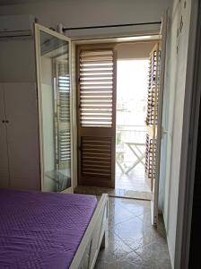 una camera con letto viola e porta scorrevole in vetro di Vacanze in Sicilia a Siculiana