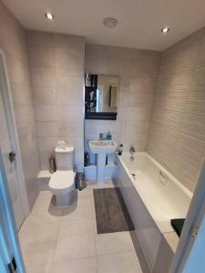 a bathroom with a tub and a toilet and a sink at 3 Bed - Modern, High Spec, Spacious Apartment in London