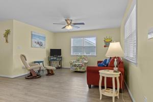 uma sala de estar com um sofá vermelho e uma cadeira em Boardwalk Shores C Duplex em Atlantic Beach