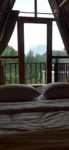 a bed with pillows in front of a window at Cabin LEHA LEHE SYARIAH Dieng in Dieng