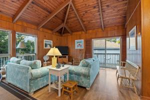 Sala de estar con 2 sofás y mesa en Dogwood Treehouse home, en Pine Knoll Shores