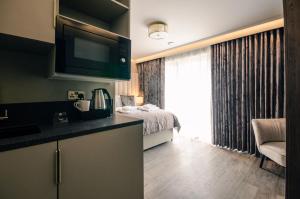Zimmer mit einem Bett und einer Küche mit einem TV in der Unterkunft Sweeney Rooms Aviemore in Aviemore