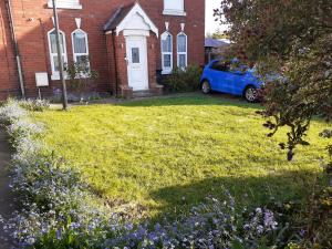 Victoria Villas في Sandycroft: سيارة زرقاء متوقفة أمام منزل من الطوب