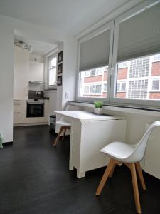 a kitchen with a table and two chairs and two windows at Apartment Jakimovski in Wuppertal