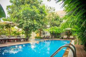 a swimming pool with tables and chairs and trees at Skyline Boutique Hotel Phnom Penh in Phnom Penh