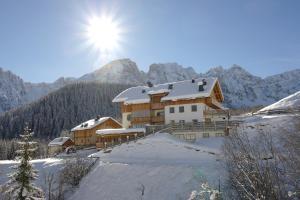 a house in the snow with the sun behind it at Tlisöra Speckstube in Frena