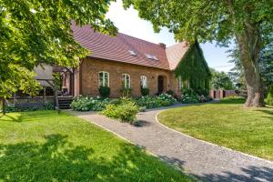 a brick house with a tree and a walkway at Stara Szkola Trzcin 20 in Trzcin