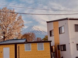una montaña cubierta de nieve en la distancia detrás de una casa en ヴィラ山間堂GrandVilla Mt Fuji view BBQ Bonfire AnnoVillas Sankando, en Fujikawaguchiko