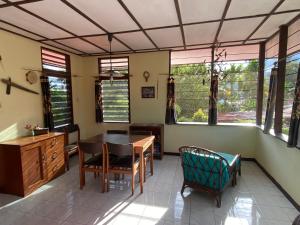 ein Esszimmer mit einem Tisch, Stühlen und Fenstern in der Unterkunft Homestay Galpera Papua in Jayapura