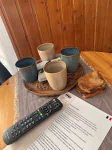 einen Tisch mit drei Kaffeetassen und einer Fernbedienung in der Unterkunft Le Skäli in Thollon