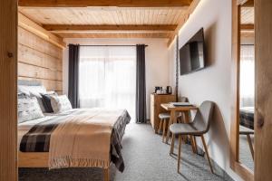 a bedroom with a bed and a desk and a television at Willa Malinowa in Zakopane