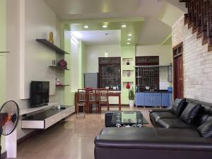 uma sala de estar com um sofá preto e uma televisão em Su Homestay em Cao Bang