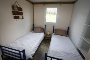 two beds in a small room with a window at Camping du Villard in Thorame-Basse