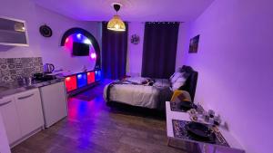 Le cocon du Nil jolie studio في دويه: غرفة أرجوانية مع سرير ومطبخ مع أضواء أرجوانية