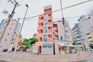 um edifício rosa alto numa rua da cidade em ピースリー安里201 em Tomari