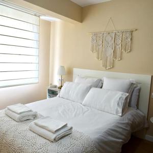 ein weißes Bett mit zwei Handtüchern darüber in der Unterkunft Piso Riazor 4 habitaciones in A Coruña
