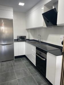 eine Küche mit weißen Schränken und einem Kühlschrank aus Edelstahl in der Unterkunft Apartamento Luli in Calpe