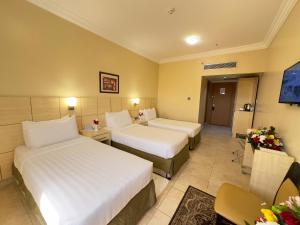 a hotel room with two beds and a table at Al Massa Bader Hotel in Makkah