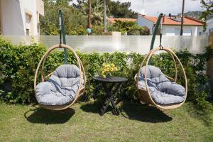 twee schommelstoelen en een tafel in de tuin bij JASMINE STUDIOS POTOS in Potos