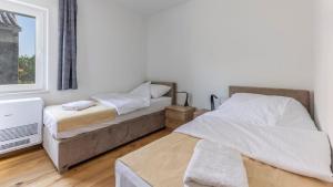 a bedroom with two beds and a window at Beautiful new Apartment Ancora 2 in Nerezine