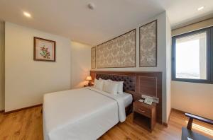 Un dormitorio con una gran cama blanca y una ventana en Imperial Nha Trang en Nha Trang