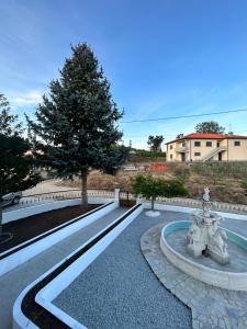 a fountain in a park with a tree and a building at Casa Vicente in Lamego