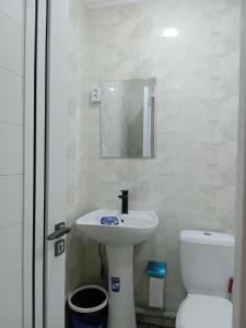 ein Badezimmer mit einem Waschbecken, einem WC und einem Spiegel in der Unterkunft GUESTO HOSTEL in Taschkent