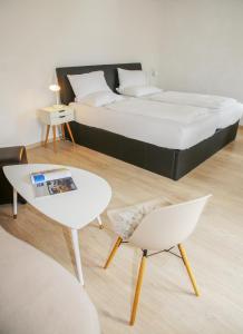 a bedroom with a bed and a table and a chair at Hotel Sonnenhof - bed & breakfast & appartements in Innsbruck