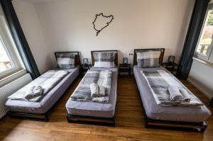 3 camas están sentadas en una habitación con una pared en Südschleife Appartements - App. 2 - WLAN - Direkt am Ring, en Reimerath