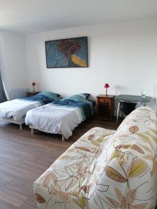 Cette chambre comprend deux lits et une table avec un tableau. dans l'établissement logement entier spacieux et confortable à 1 h de Paris, à Courtenay
