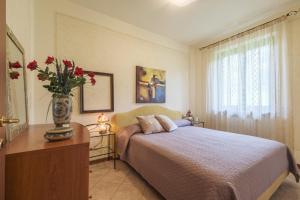 a bedroom with a bed and a vase with red flowers at De Gasperi 14 in Sale Marasino