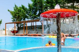 un enfant jouant dans une piscine avec une fontaine dans l'établissement 6 Milje Hotel, à Ksamil