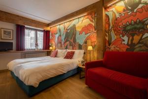 um quarto com uma cama grande e um sofá vermelho em Hotel & Ristorante Serenella em Breuil-Cervinia