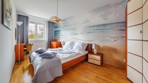 a bedroom with a bed with a painting of the ocean at Apartamenty Sun & Snow Kasprowicza in Kołobrzeg