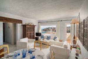 Elle comprend un salon doté d'un mobilier blanc et d'une grande fenêtre. dans l'établissement Casa Silvana by Wonderful Italy, à Porto Cervo
