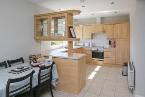 a kitchen with wooden cabinets and a table with chairs at Briglane Cottage in Kirkistown