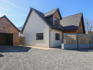 a white house with a black roof and a driveway at Woodend Croft in Ellon