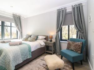 a bedroom with a bed and a chair and windows at Woodend Croft in Ellon