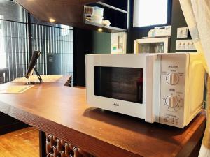 a microwave sitting on top of a wooden table at Bar & Hotel Colors MIYAJIMA in Hatsukaichi
